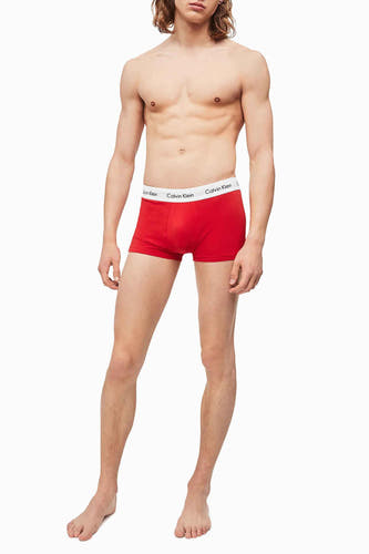 Rode boxershort van Calvin Klein, gedragen door een man met ontbloot bovenlijf, staand tegen een witte achtergrond.