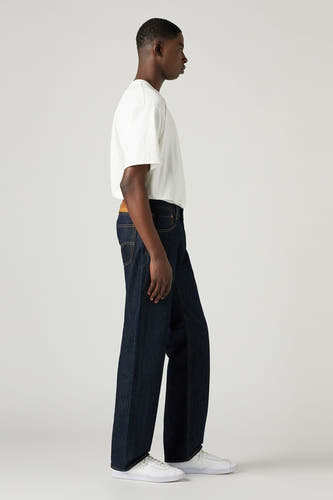 Donkerblauwe straight jeans van Levi's, gedragen met een wit T-shirt en witte sneakers, in zijaanzicht.
