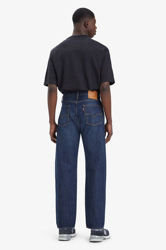 Jean bleu droit de Levi's, vu de derrière, combiné avec un T-shirt noir et des baskets bleues.