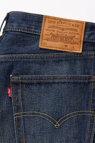 Jean bleu droit de Levi's®, avec une patch en cuir et des points caractéristiques sur la poche arrière.