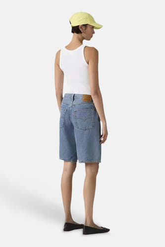 Blauwe mid-lengte denim shorts van Levi's, achterzijde met zakken en label, gedragen met wit tanktop en gele pet