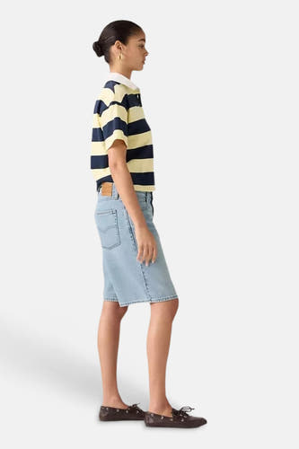 Lichtblauwe denim shorts van Levi's® in zijprofiel, met zakken en gestikte zoom, gedragen met gestreept shirt en bruine loafers