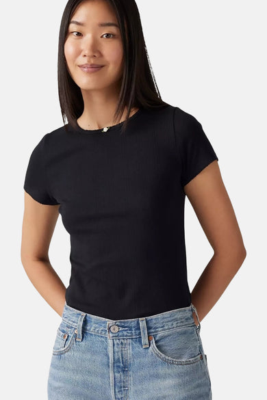 Vrouw met zwart geribbeld T-shirt en blauwe jeans.
