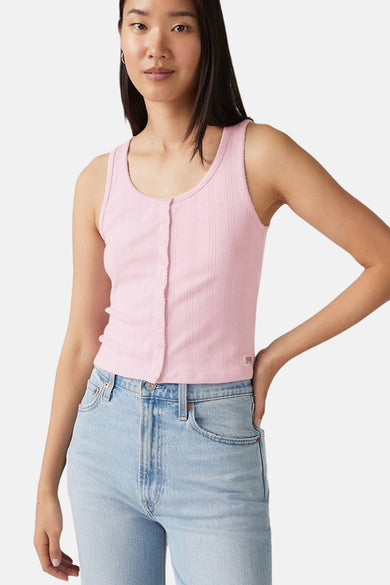 Vrouw draagt roze ribgebreide top en blauwe jeans.