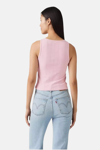 Vrouw in lichtblauwe jeans en roze ribgebreide top, achterkant.
