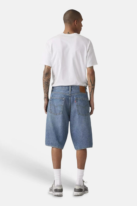 Short en jean bleu clair de Levi's®, dos, avec poches et patch en cuir, porté par un homme avec un t-shirt blanc.