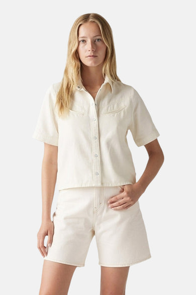 Vrouw in crèmekleurige denim outfit met korte mouwen en korte broek.