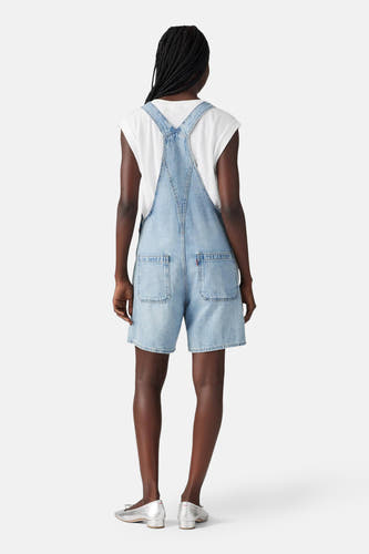 Playsuit van lichtblauw denim van Levi's, met korte pijpen en rugzakbandjes, gedragen over een wit T-shirt, achterkant.