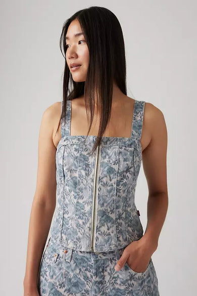 Een Aziatische vrouw draagt een blauw-wit topje met ritssluiting en broek met bloemmotief.