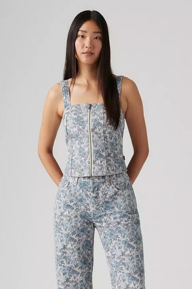 Vrouw met lange donkere haren, bloemige jeansset met ritstop.