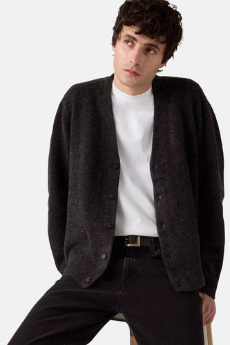 Veste grise de Levi's portée sur un chemisier blanc avec des jeans noirs et une ceinture à boucle dorée.