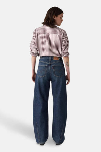 Jean spécial fit en denim bleu marine de Levi's®, vu de derrière avec un chemisier rayé.