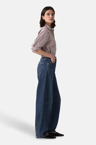 Jean spécial fit en denim bleu marine de Levi's®, avec des jambes larges et porté avec un chemisier rayé.