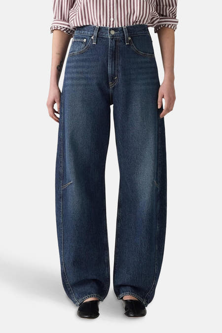 Jean denim bleu marine spécial ajusté de Levi's, avec des jambes larges et porté avec un chemise rayée.