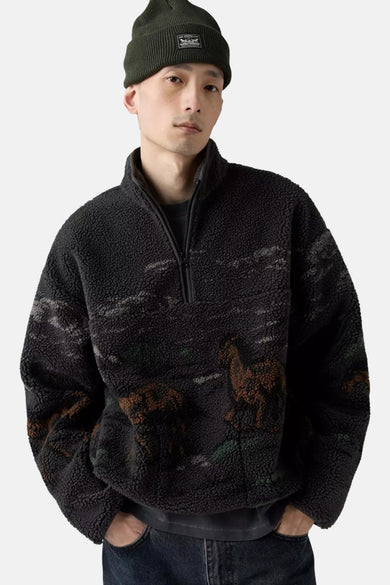Fleece noir de Levi's avec un motif de chevaux et une fermeture éclair haute, porté avec un chapeau vert.