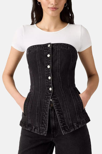 Zwarte denim tuniek van Levi's, gedragen over een wit shirt met korte mouwen, met zilverkleurige knopen en steekzakken.
