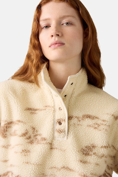 Vrouw draagt beige fleece trui met knoopsluiting.