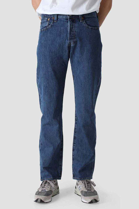 Jean bleu droit de Levi's, avec une texture denim et porté avec des baskets grises.