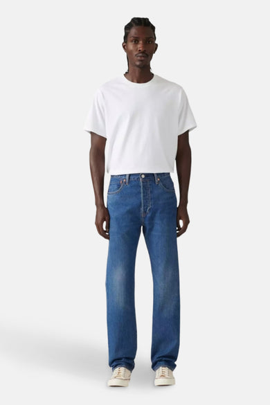 Jean droit bleu denim mid Levi's®, porté avec un T-shirt blanc et des baskets crème.