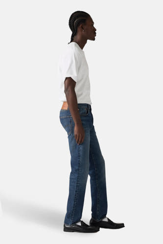 Donkerblauwe denim jeans straight van Levi's®, gedragen met een wit T-shirt en zwarte loafers, in zijaanzicht.
