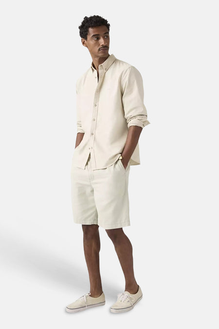 Short de couleur écru de Levi's® portée par un homme, associée à une chemise écrue et des baskets de couleur crème.