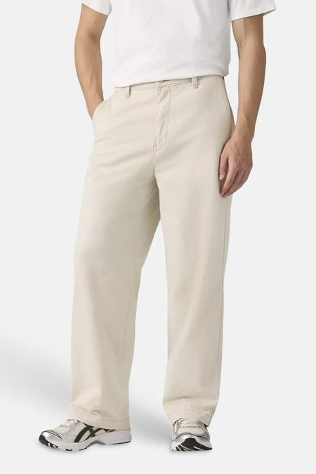 Chino beige de Levi's® avec coupe décontractée et étiquette rouge, porté par un homme avec un t-shirt blanc, de profil.
