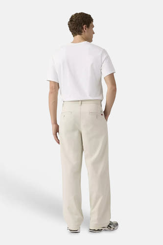 Chino beige à jambes larges de Levi's®, avec poches passepoilées, porté par un homme avec un t-shirt blanc et des baskets.