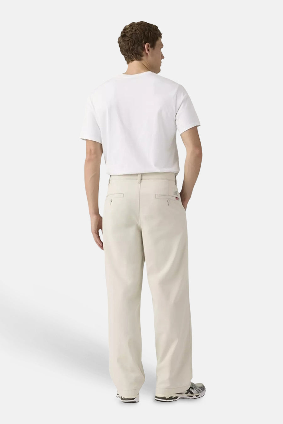 Chino beige à jambes larges de Levi's®, avec poches passepoilées, porté par un homme avec un t-shirt blanc et des baskets.