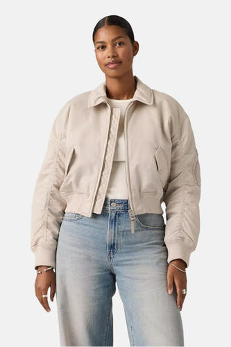 Veste courte grise de Levi's, avec fermeture éclair et poches, portée avec un haut blanc et un jean bleu clair.