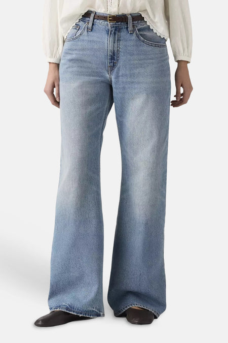 Jean bootcut bleu clair en denim de Levi's® avec un délavage clair, des jambes évasées et des surpiqûres visibles sur les poches arrière, porté par un mannequin de dos avec un chemisier blanc.