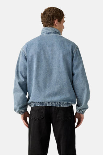 Manteau de denim court de Levi's, montré du dos, avec un zip frangé et un pantalon foncé.