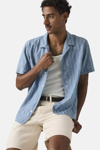 Chemise bleu clair à manches courtes de Levi's®, avec une fine structure côtelée, un col ouvert et portée sur une chemise blanche.