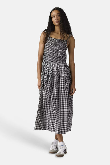 Robe longue à carreaux noirs et blancs de Levi's® avec corsage smocké et fines bretelles, portée par un mannequin assis.
