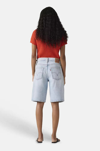 Lichtblauwe denim shorts van Levi's® van achteren gezien, gedragen met een rood gebreid shirt en zwarte sandalen.