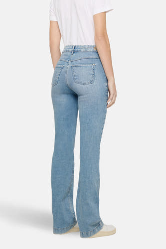 Lichtblauwe bootcut jeans van MAC, met achterzakken en gedragen met een wit T-shirt.
