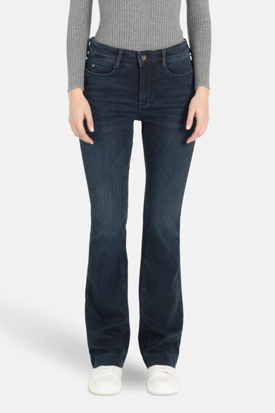 Jean bootcut bleu marine en denim de MAC, associé à une chemise grise et des baskets blanches.