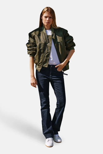 Jean bootcut bleu marine de MAC, associé à une veste bomber vert olive et des baskets blanches.