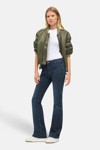 Jean bootcut en denim bleu marine de MAC, avec un modèle portant un T-shirt blanc et une veste bomber vert olive.