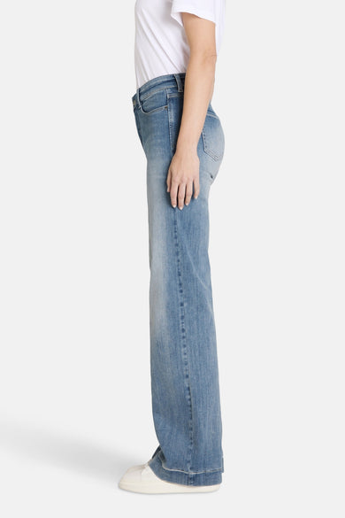Jean décontracté en denim bleu clair de MAC, avec un lavage lisse et des baskets blanches.