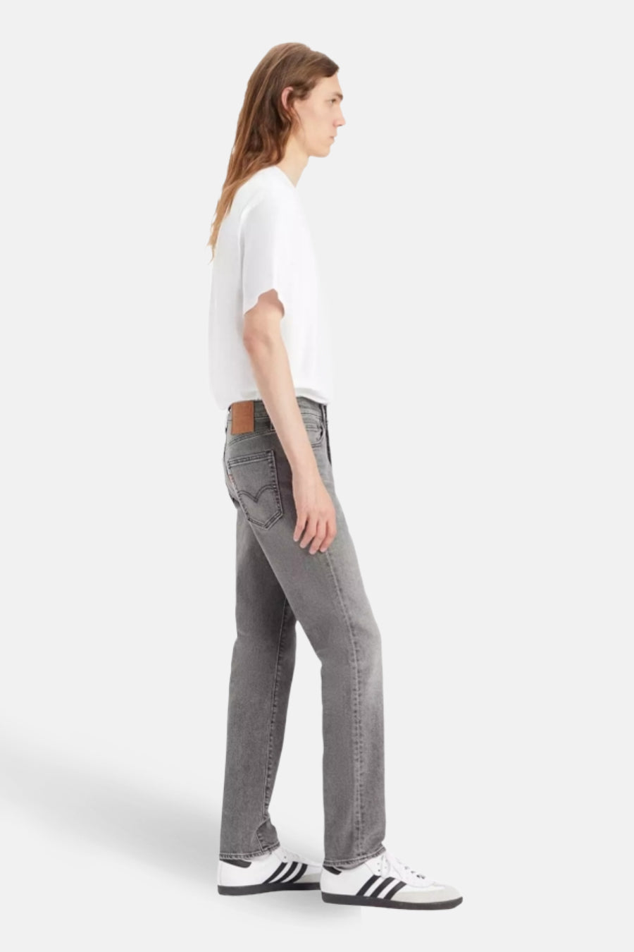 Jean slim fit gris de Levi's, porté avec un T-shirt blanc et des baskets blanches, en vue latérale.