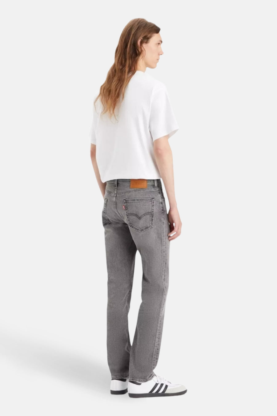 Jean slim fit gris de Levi's, avec une étiquette en cuir marron sur la ceinture, porté avec un T-shirt blanc et des baskets.
