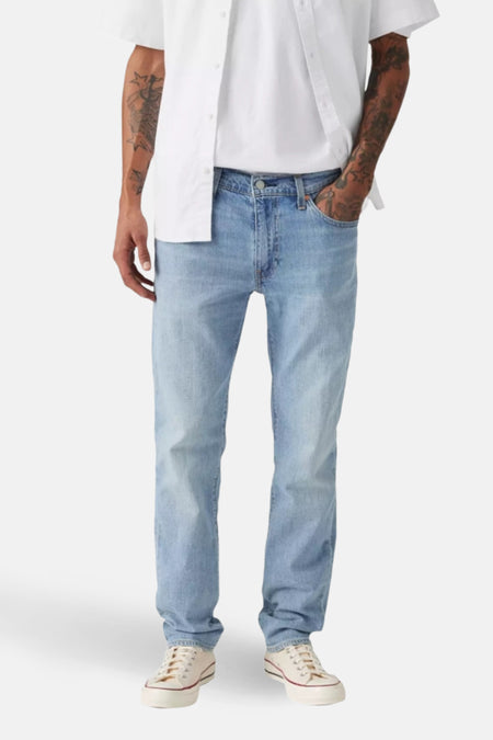 Man met lichte jeans, wit shirt en witte sneakers.