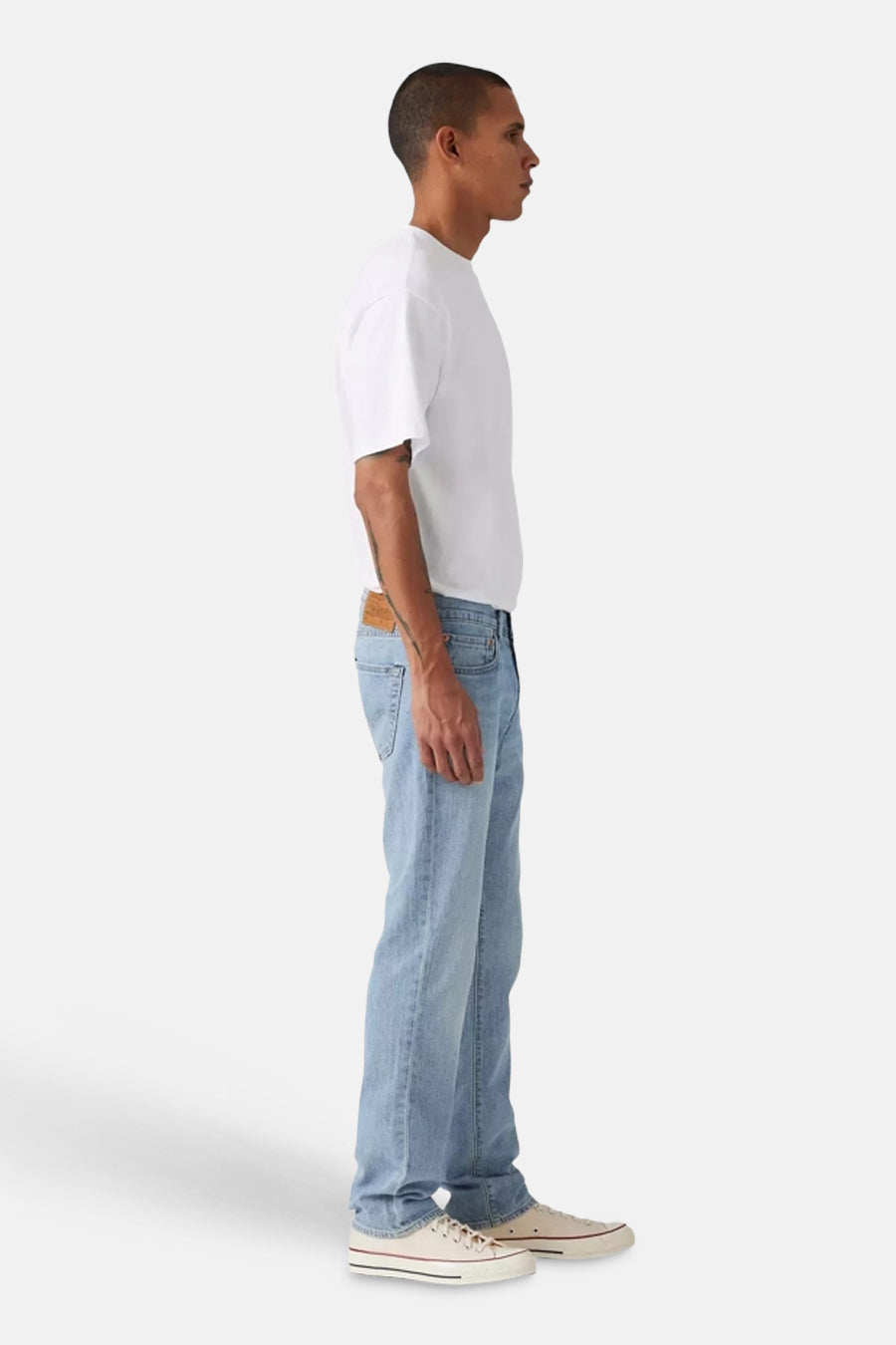 Jean slim bleu clair de Levi's, vu de côté, associé à un t-shirt blanc et des baskets de couleur crème.