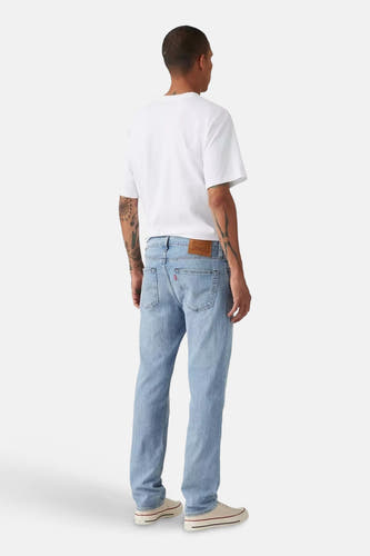 Jean slim bleu clair en denim de Levi's, vu de dos, avec un t-shirt blanc et des chaussures blanches.
