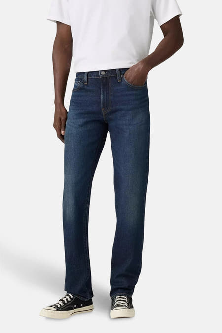 Jean slim fit bleu marine de Levi's, porté avec un T-shirt blanc et des chaussures en toile noires.