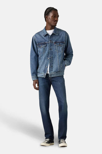 Jean slim fit en denim bleu marine de Levi's, associé à une veste en cuir et des baskets noires.