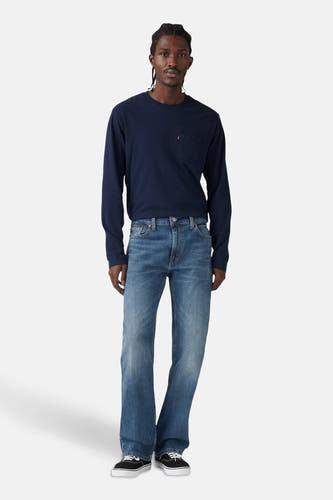 Jean bootcut en denim bleu de Levi's, porté avec un t-shirt bleu marine à longues manches et des baskets noires.