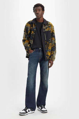 Jean bootcut en denim de Levi's, avec un délavage vintage, combiné avec un t-shirt noir et une veste polaire à imprimé.