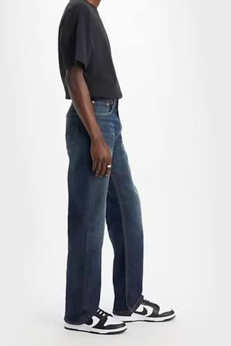 Bootcut denim jeans van Levi's, met een klassieke blauwe wassing, gecombineerd met een zwart T-shirt en zwart-witte sneakers.
