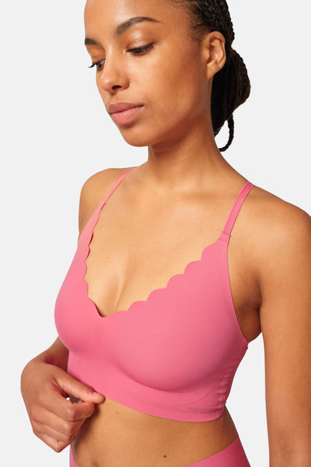 Robe de chambre rose SKINY avec bordure ondulée, portée par une femme aux cheveux tressés.